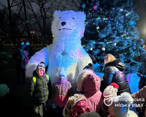 Діти фотографуються з медвідем на фоні ялинки