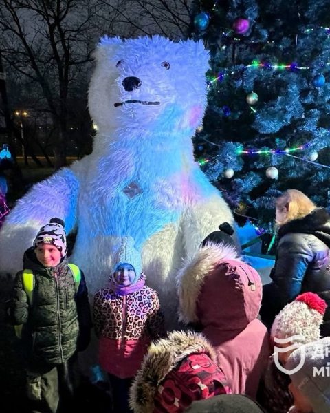 Діти фотографуються з медвідем на фоні ялинки